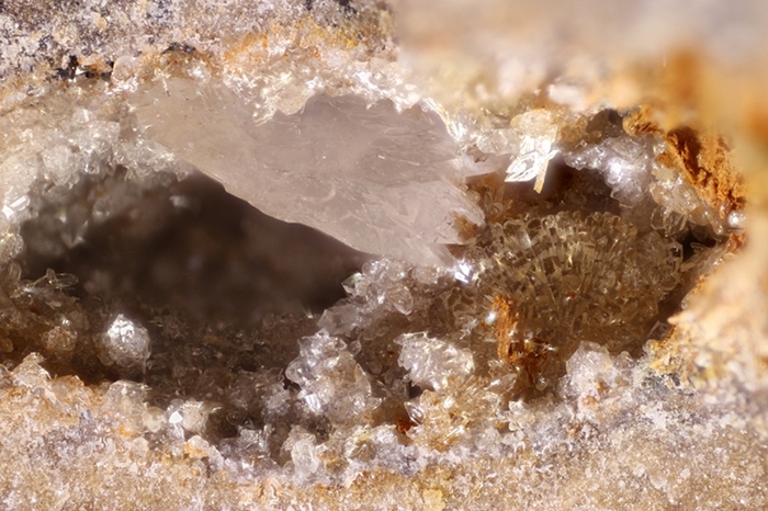 Bräunliche Hemimorphitkugel mit Calcit-Plättchen, Bildbreite 6.0 mm, Copyright F. Müller.